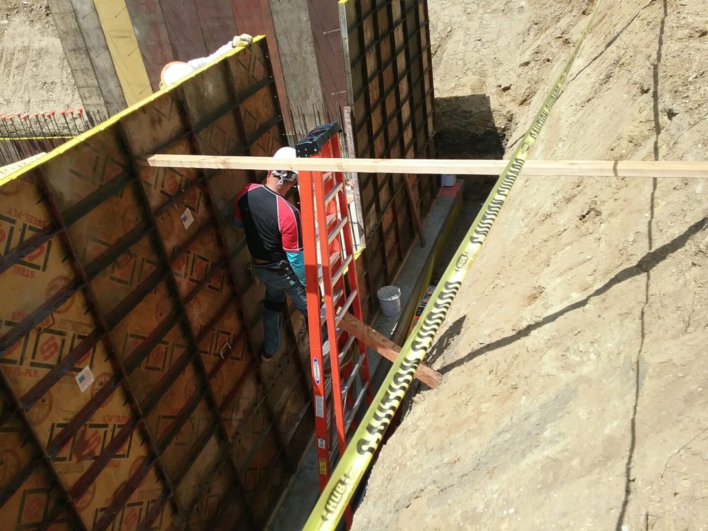 A man standing on top of a ladder next to a wall.