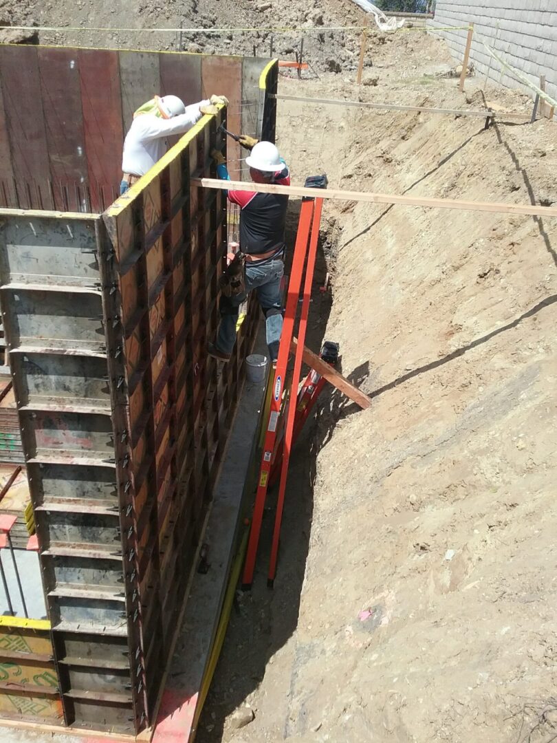 Two construction workers are working on a wall.