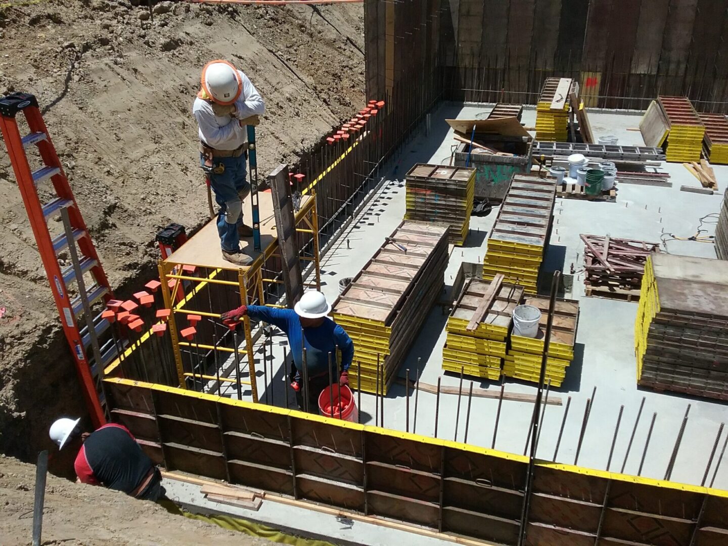 A group of construction workers standing on top of a pile.