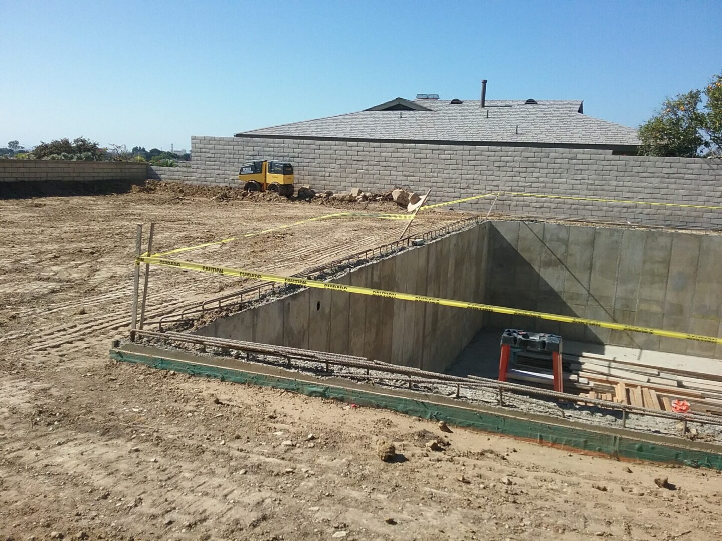 A construction site with cement walls and yellow tape.