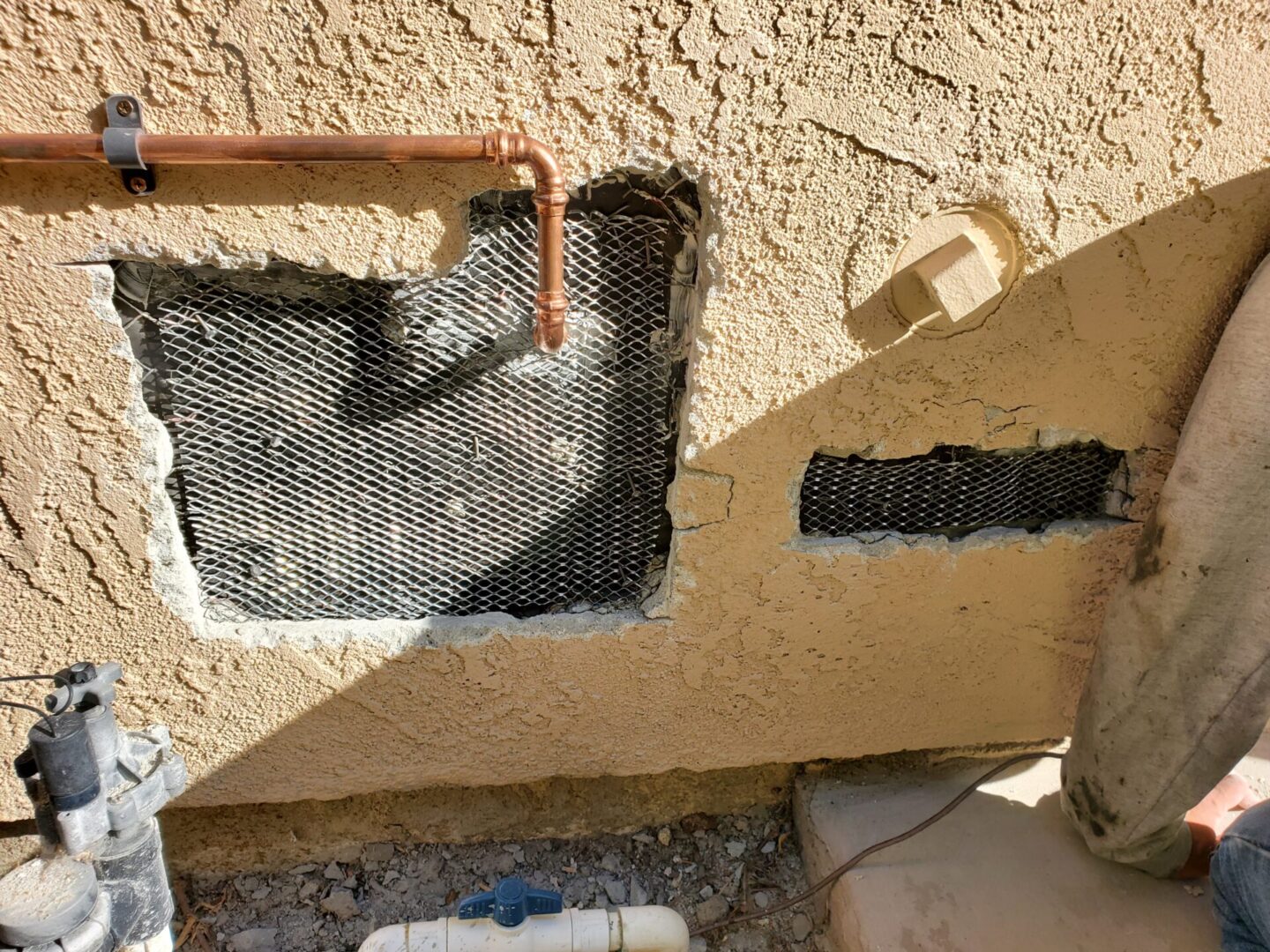 A hole in the wall with some pipes sticking out of it