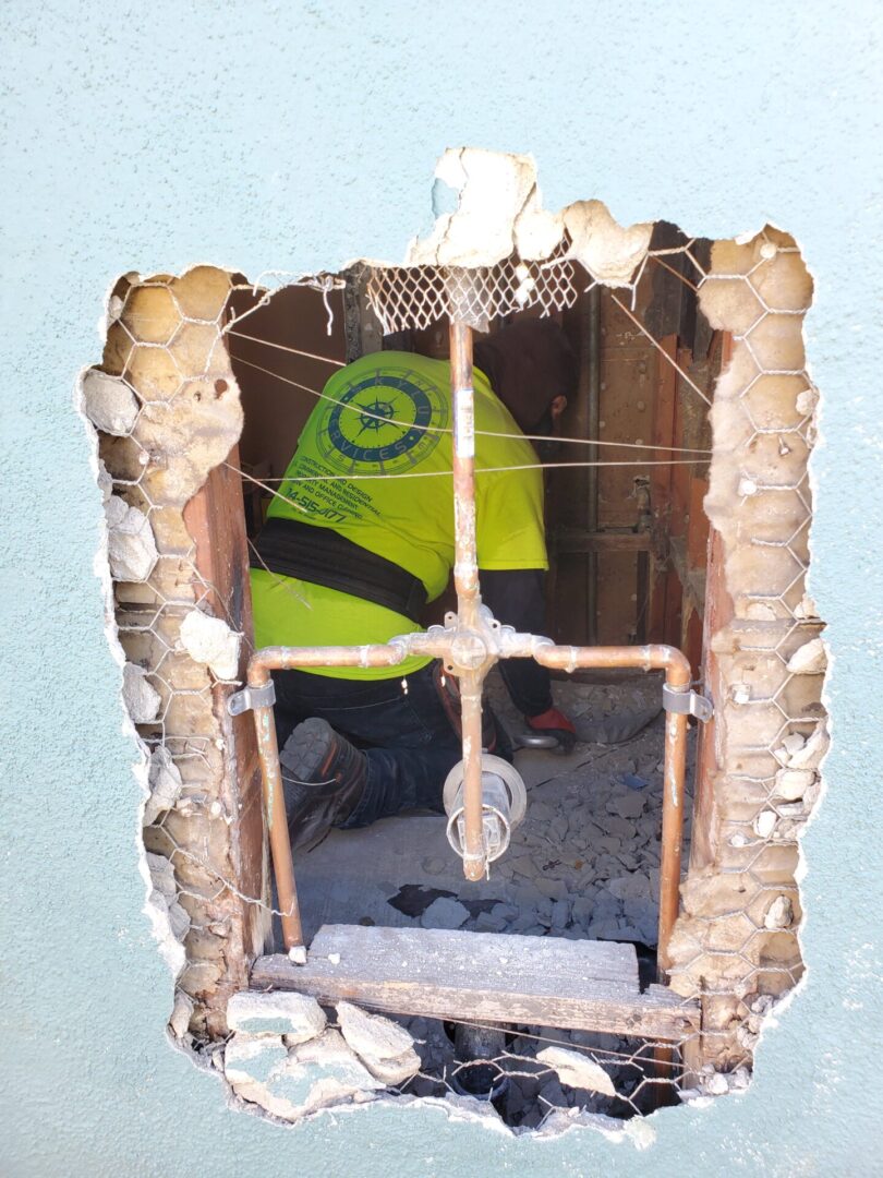 A person in yellow jacket standing inside of a hole.