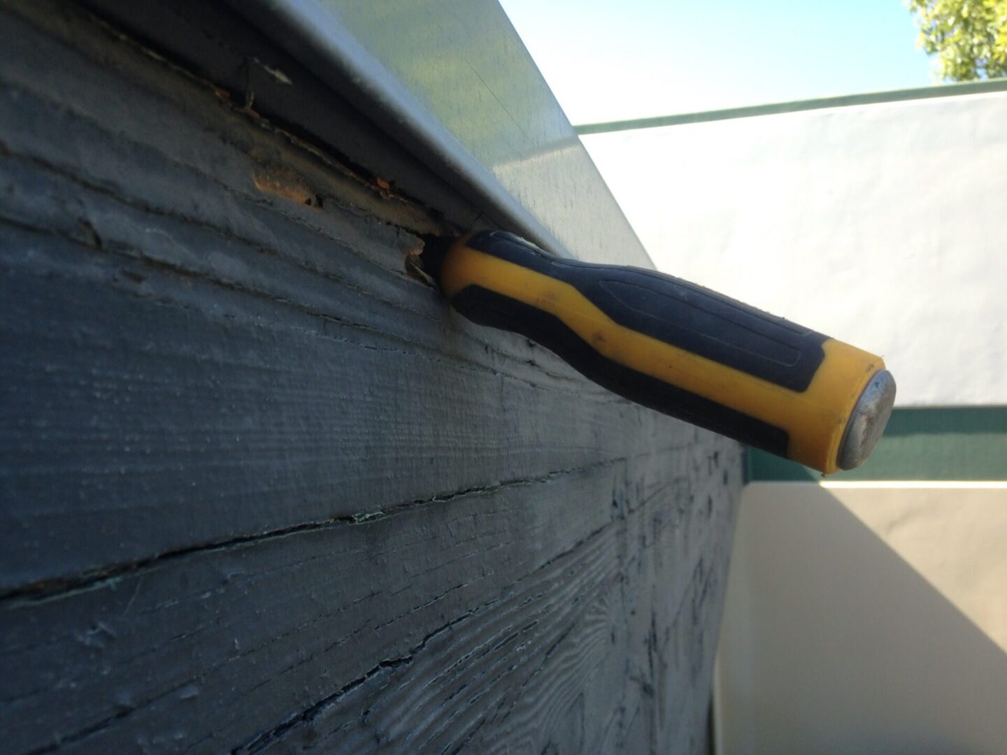 A close up of the side of a building with a screwdriver.