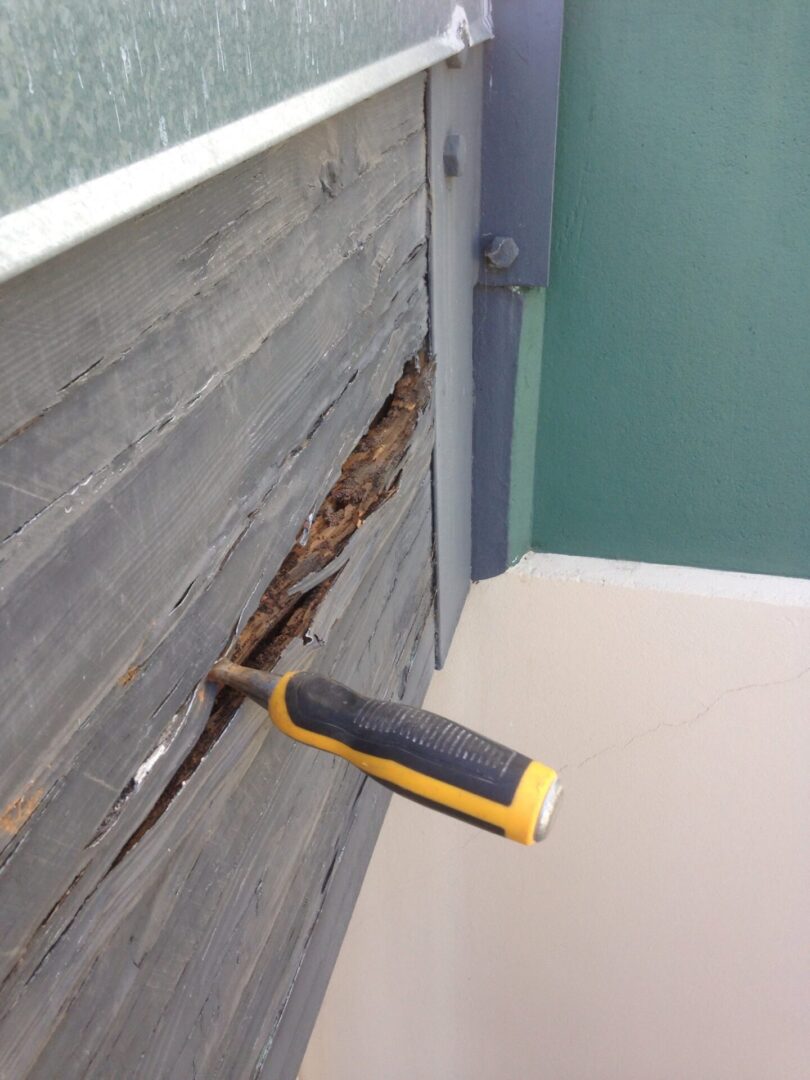 A yellow handled tool is on the side of a wooden wall.