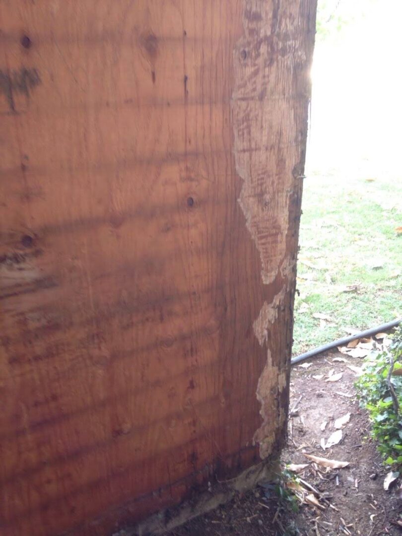 A wooden shed with some wood peeling off of it