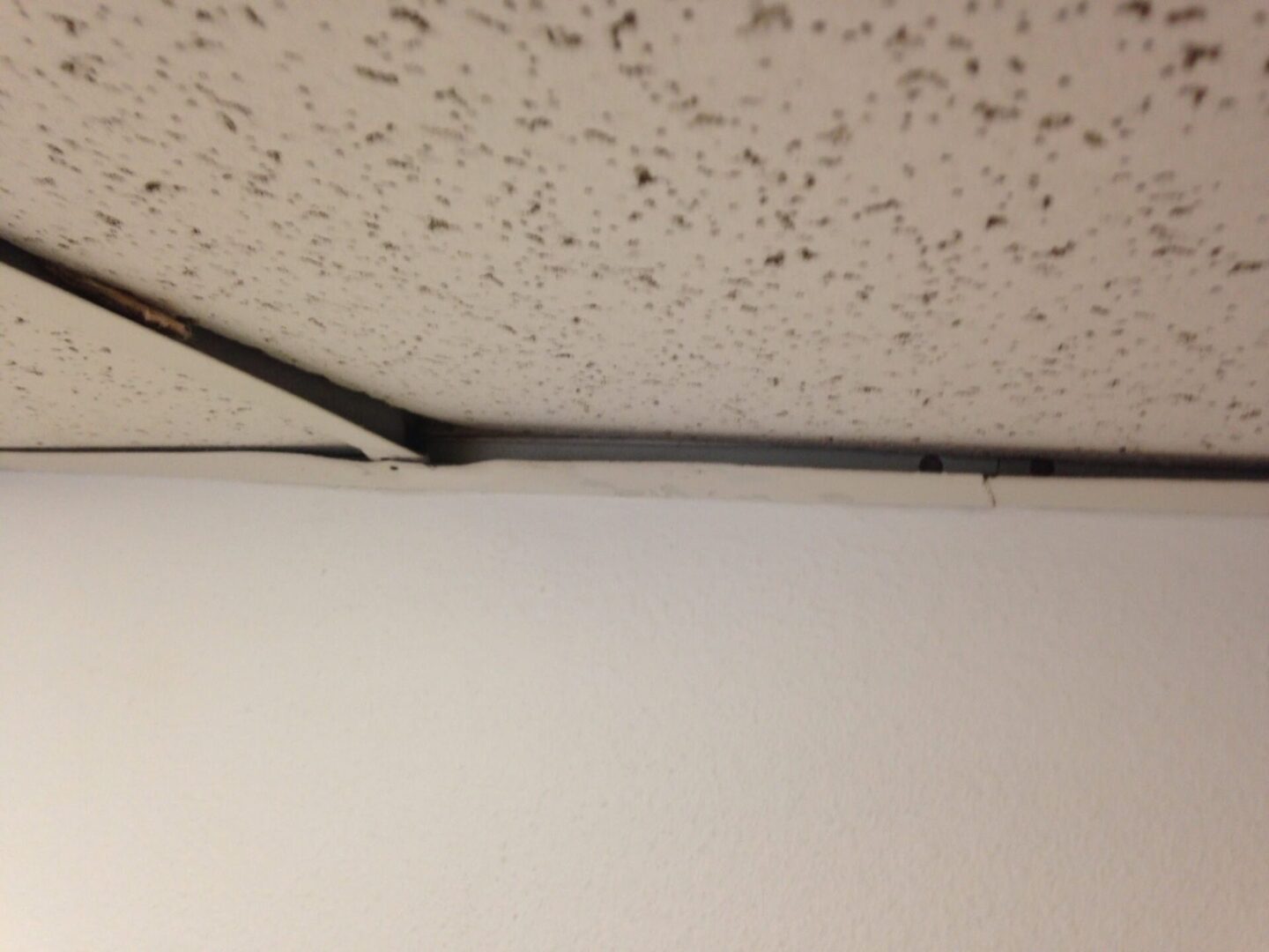 A ceiling with some holes in it and a metal pole