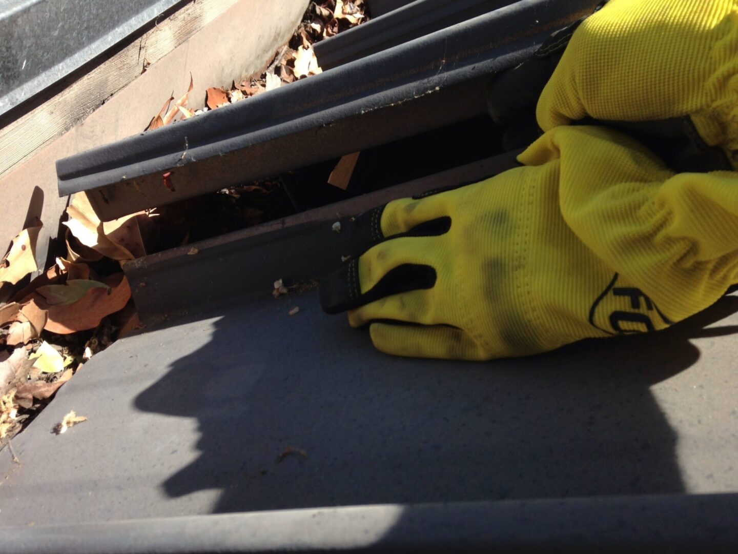 A person in yellow gloves holding onto the rail of train.