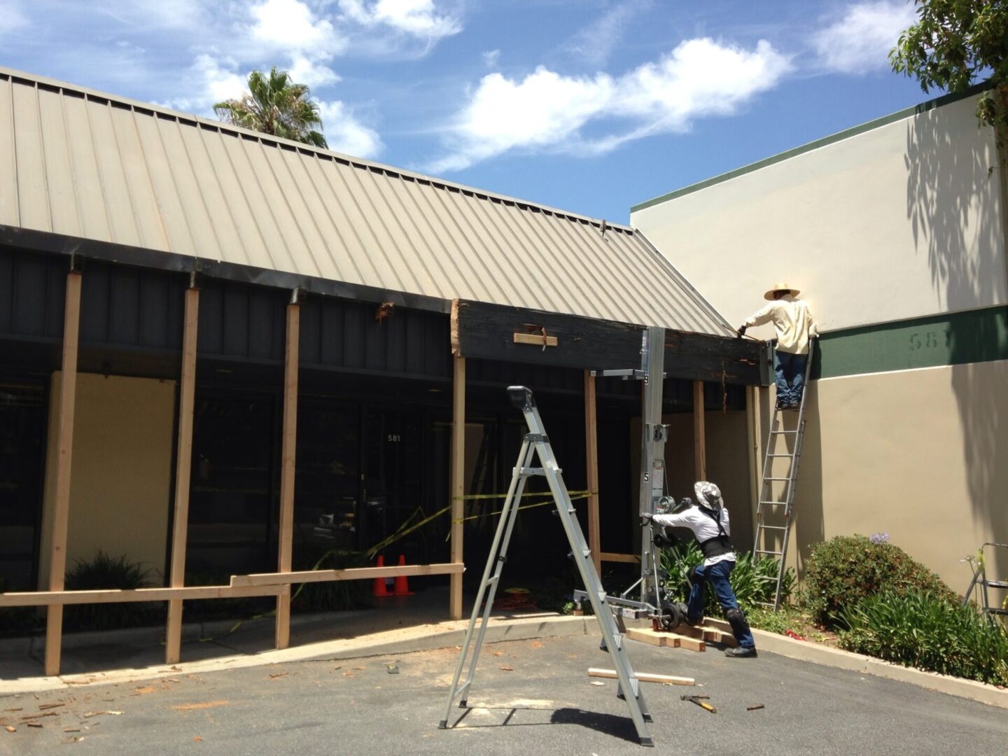 A man on a ladder painting the outside of a building.