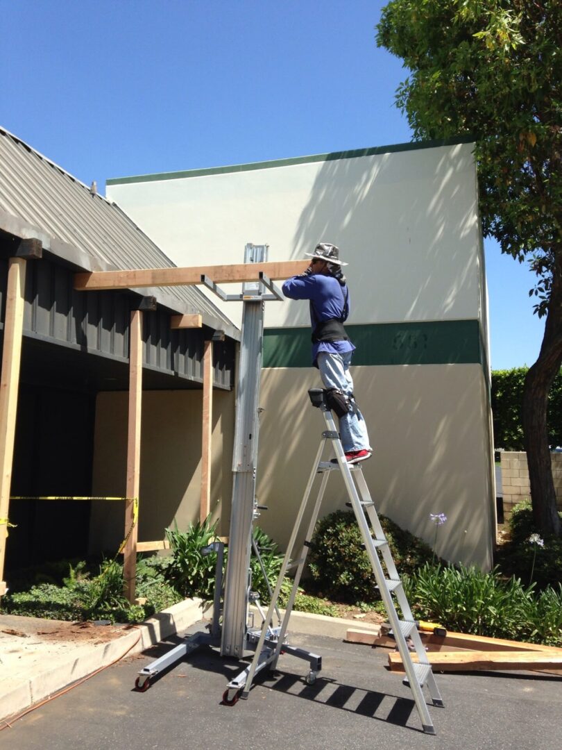 A man on a ladder working on the side of a building.