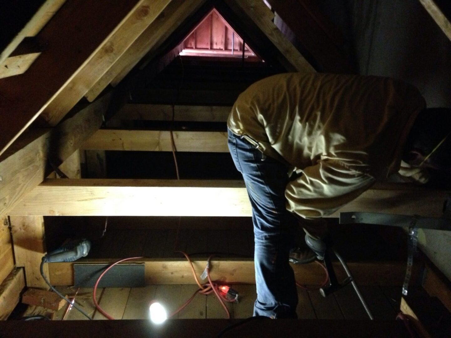 A man working on the roof of an attic.