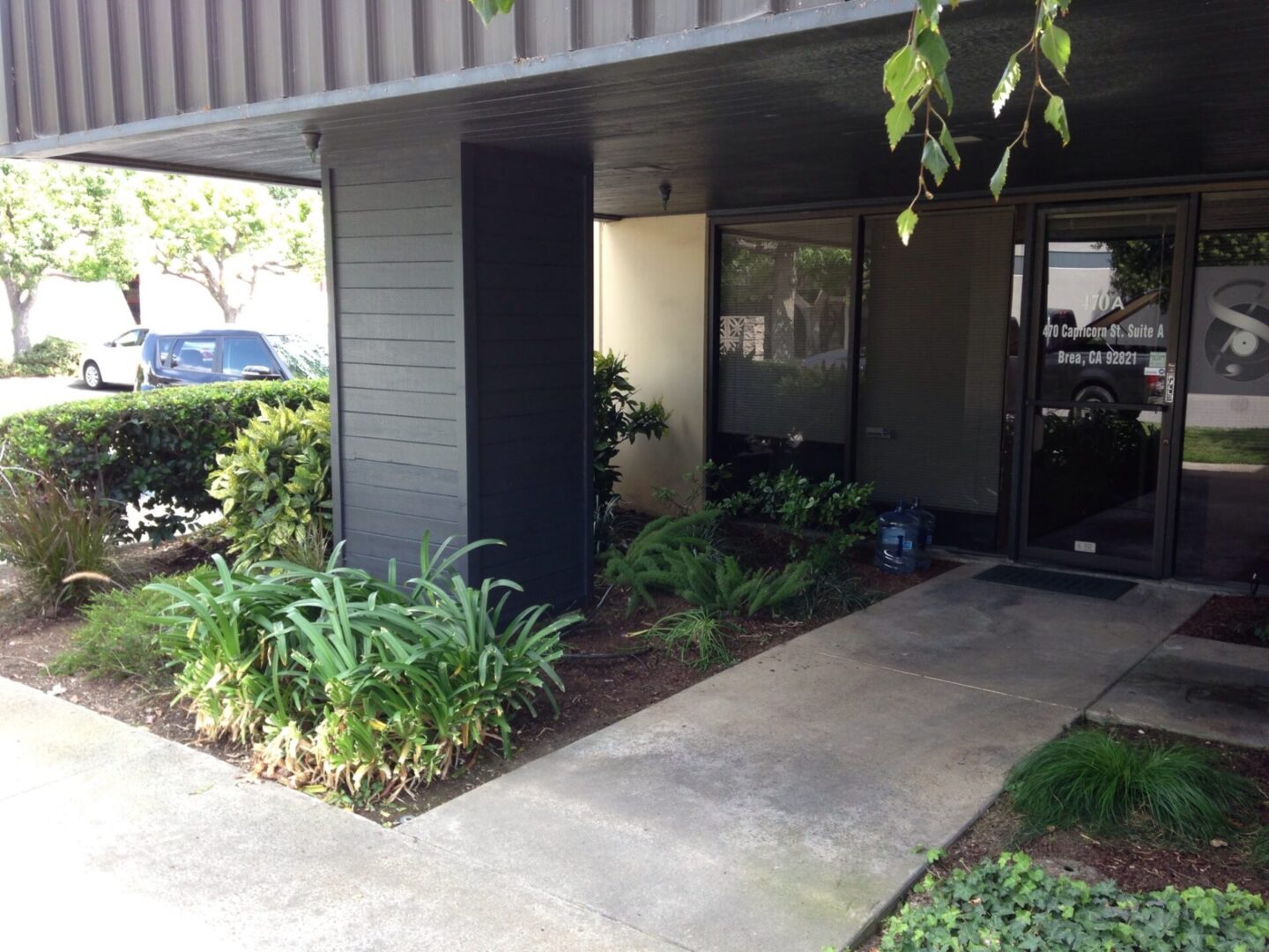 A building with plants and flowers in front of it.