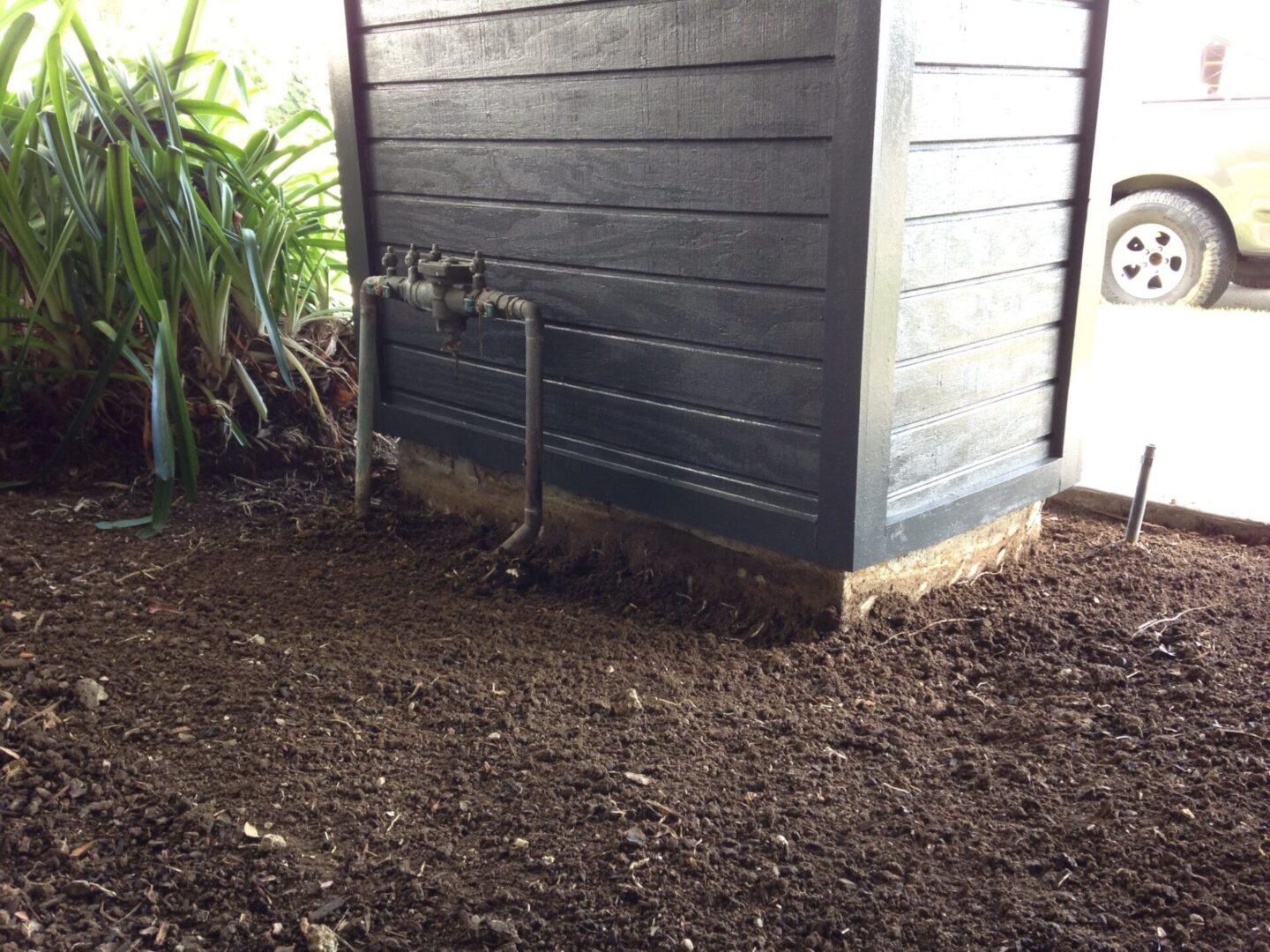 A black shed with a metal pipe in the middle of it.