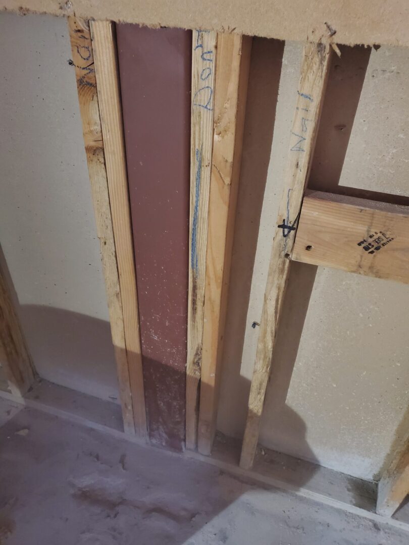 A bathroom wall being built with wood and plaster.