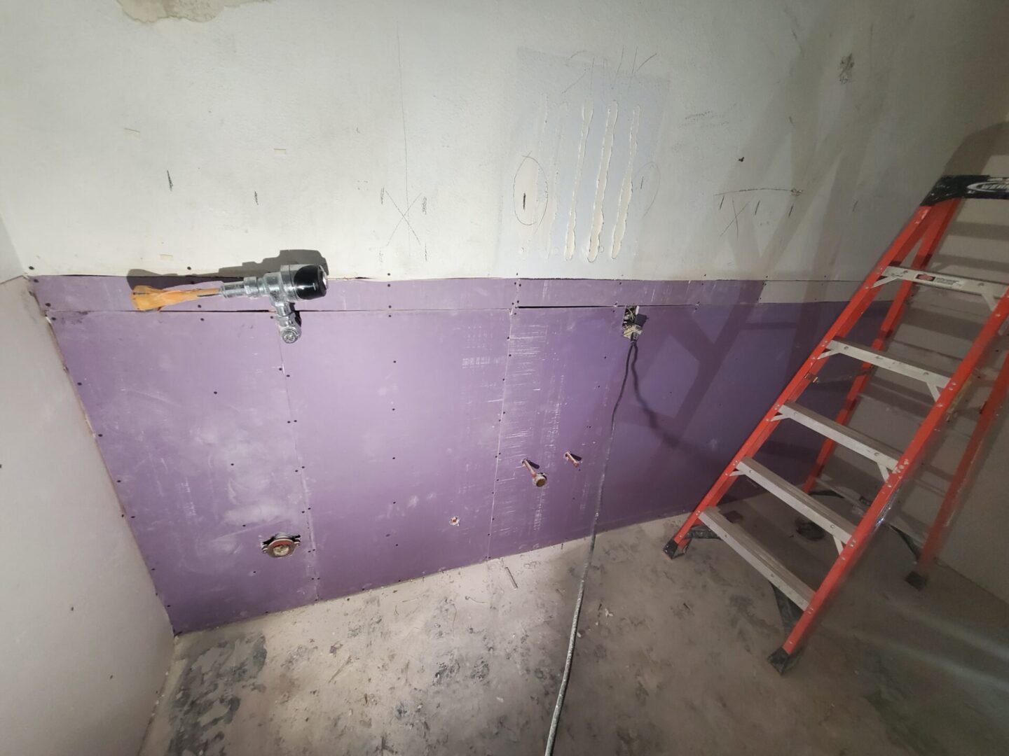 A ladder and some purple walls in a room.