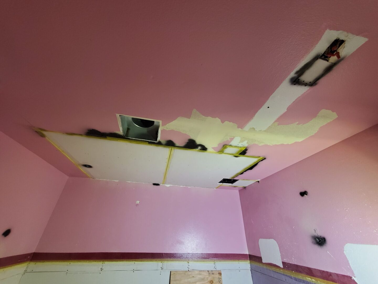 A room with pink walls and a ceiling that has been torn off.