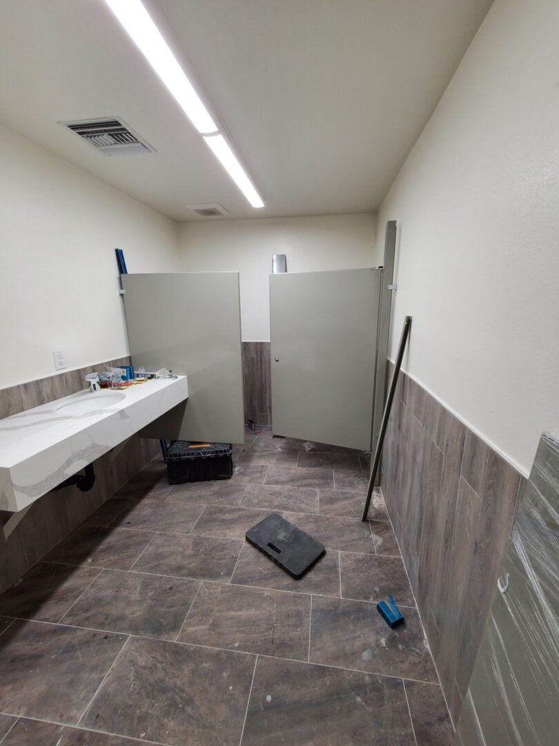 A bathroom with two stalls and a sink.