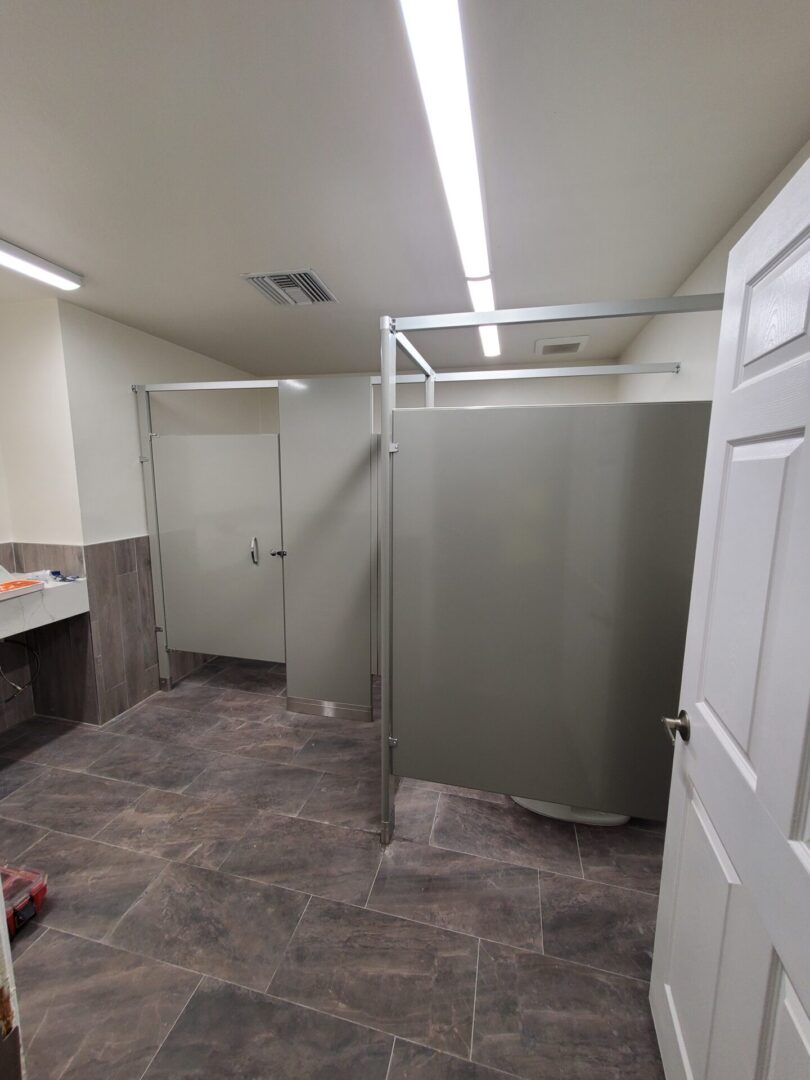 A bathroom with many stalls and sinks