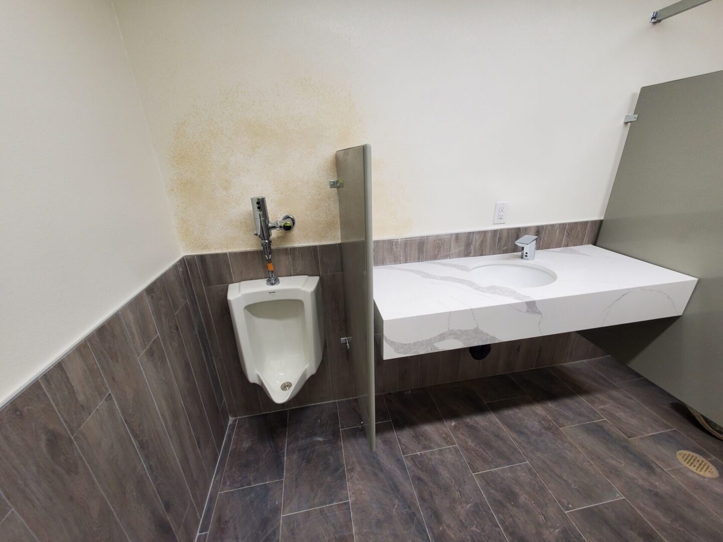 A bathroom with a urinal and sink in it