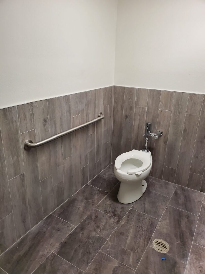 A toilet in a bathroom with wood walls.