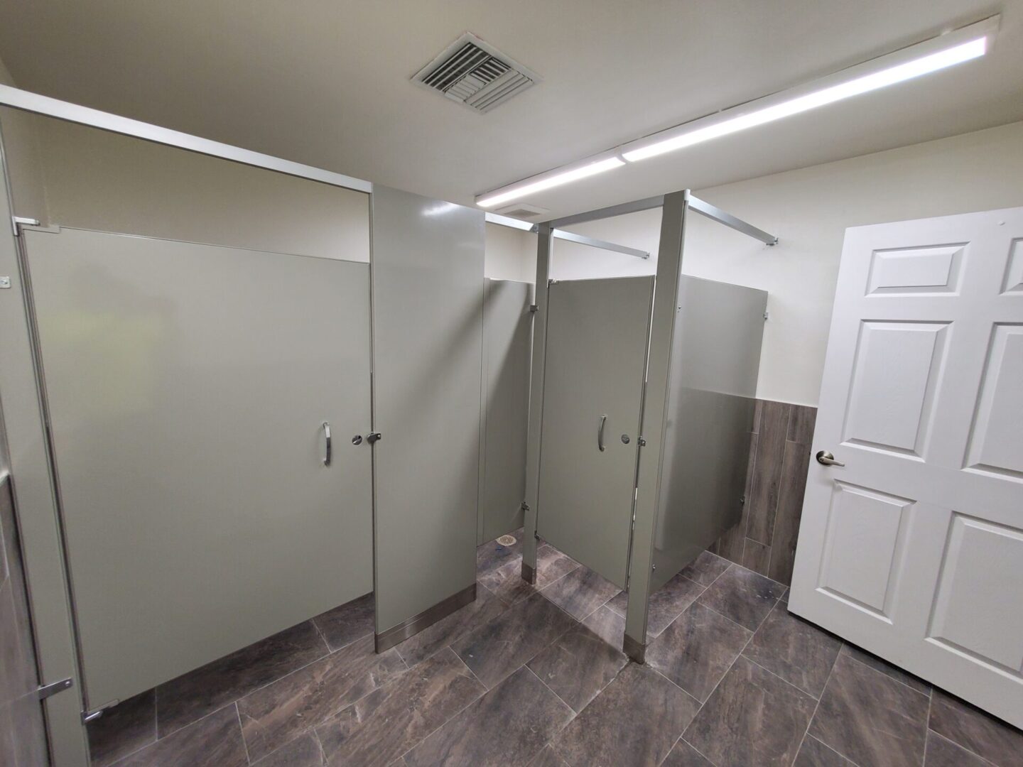 A bathroom with many stalls and doors.