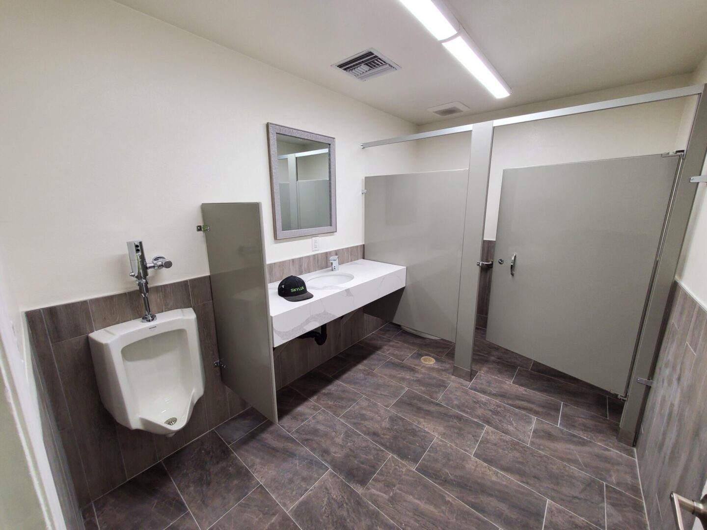 A bathroom with urinal and mirror in it