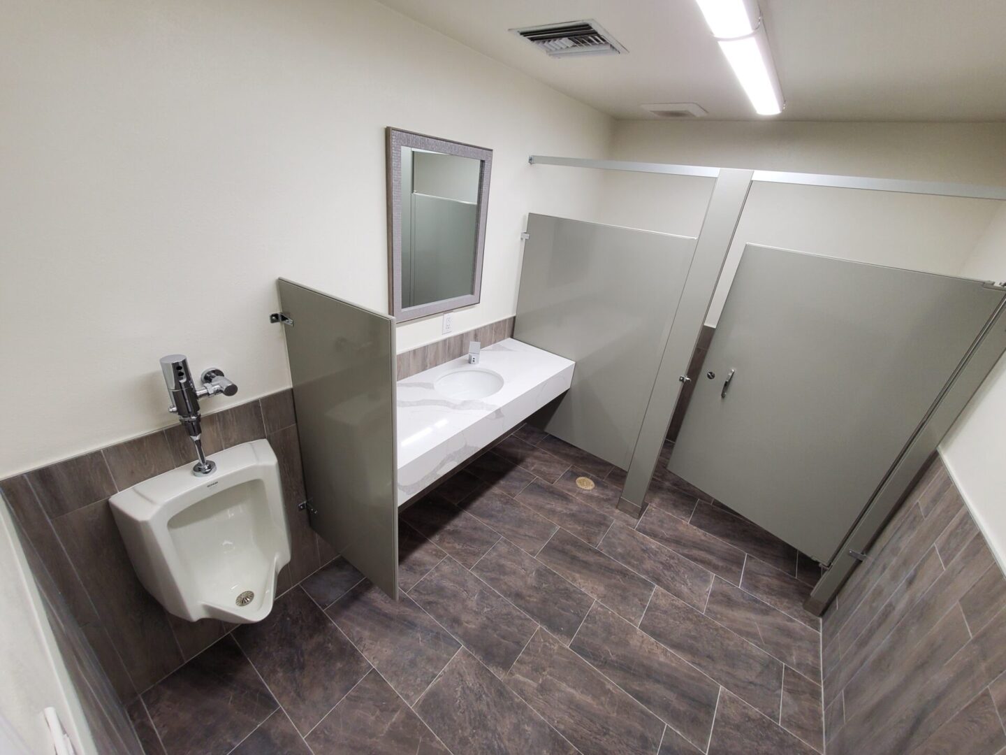 A bathroom with urinal and mirror in it