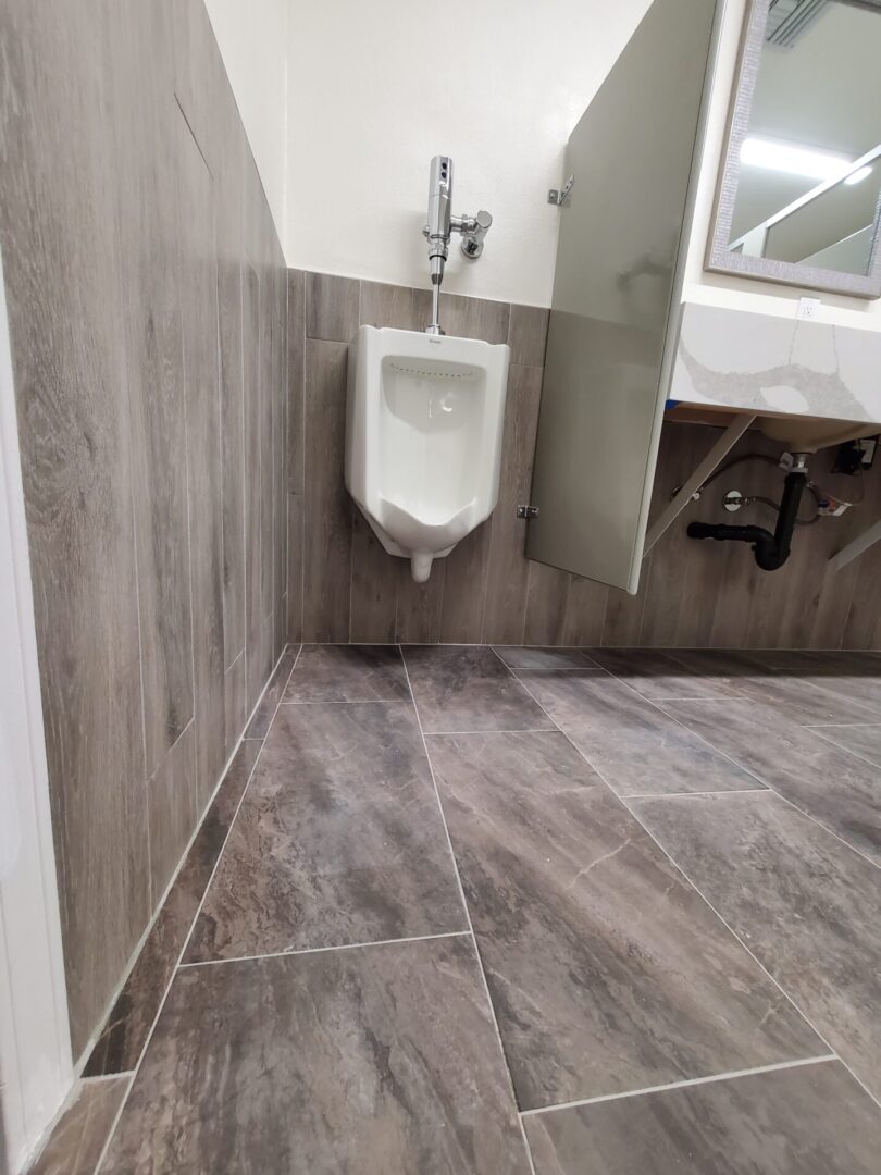 A bathroom with wood floors and a urinal.