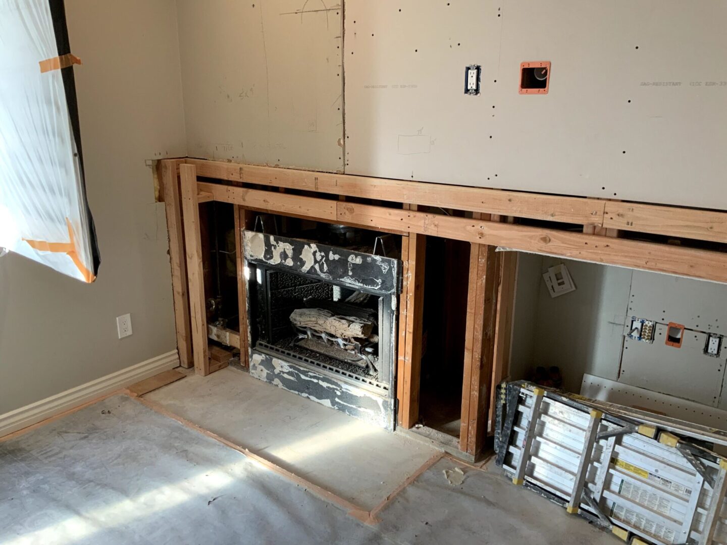 A room with a fireplace and some construction materials.