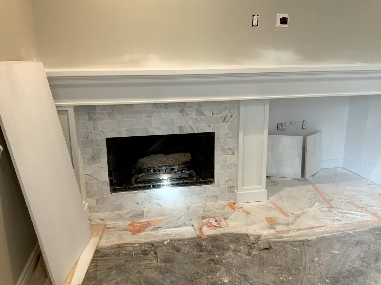 A fireplace in the corner of a room with marble tile.