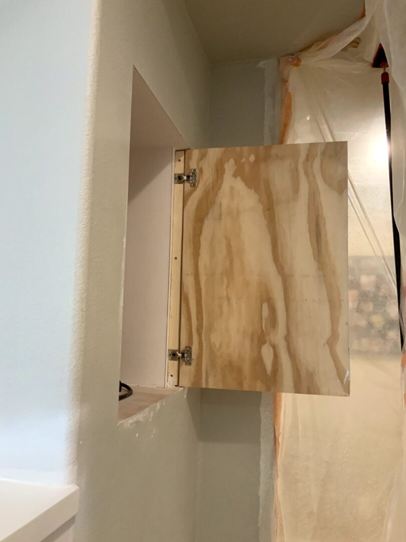 A wooden cabinet door in the corner of a bathroom.