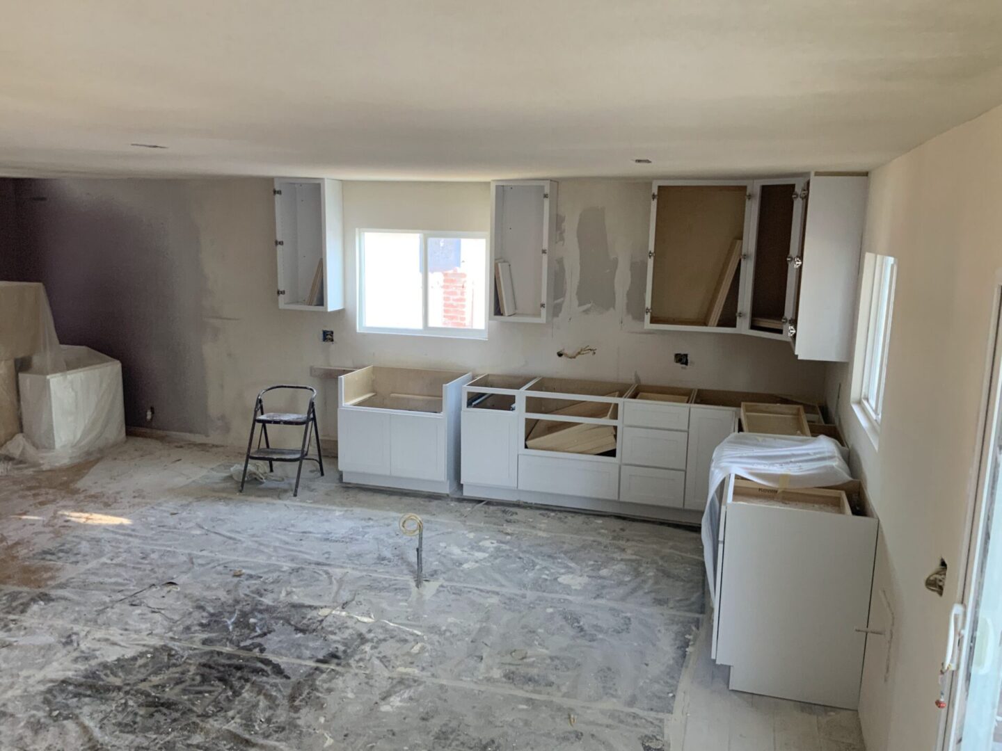 A kitchen being remodeled with white cabinets and appliances.