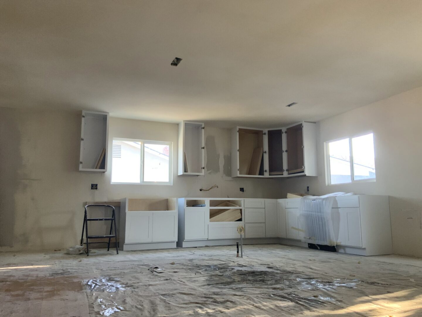 A kitchen with white cabinets and walls in the middle of construction.