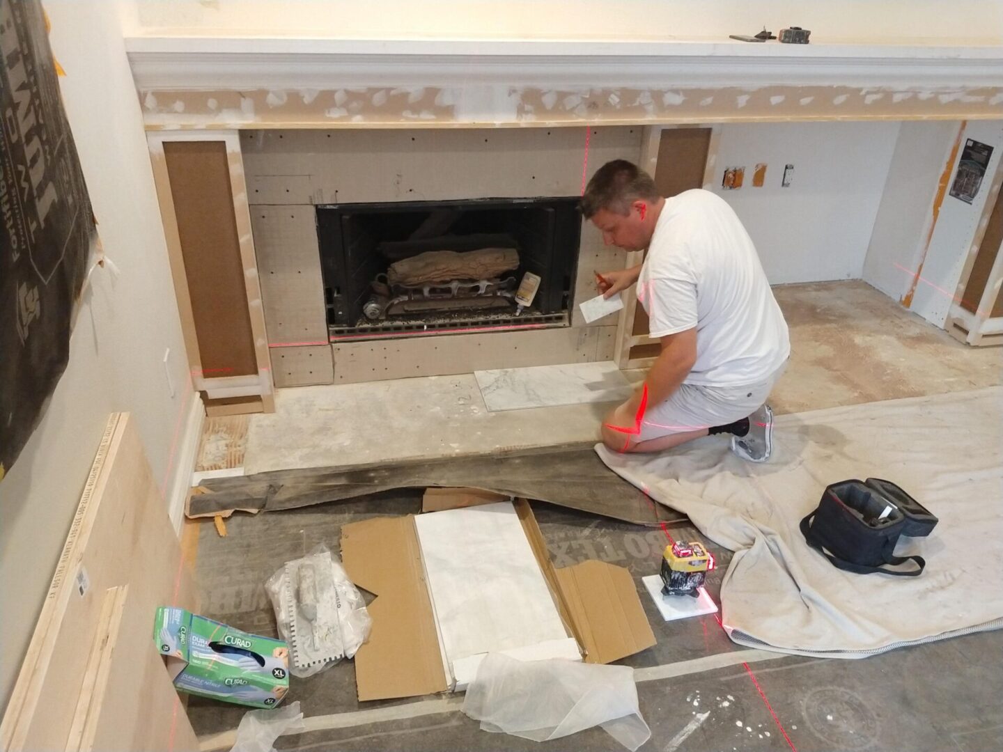 A man is painting the fireplace in his home.