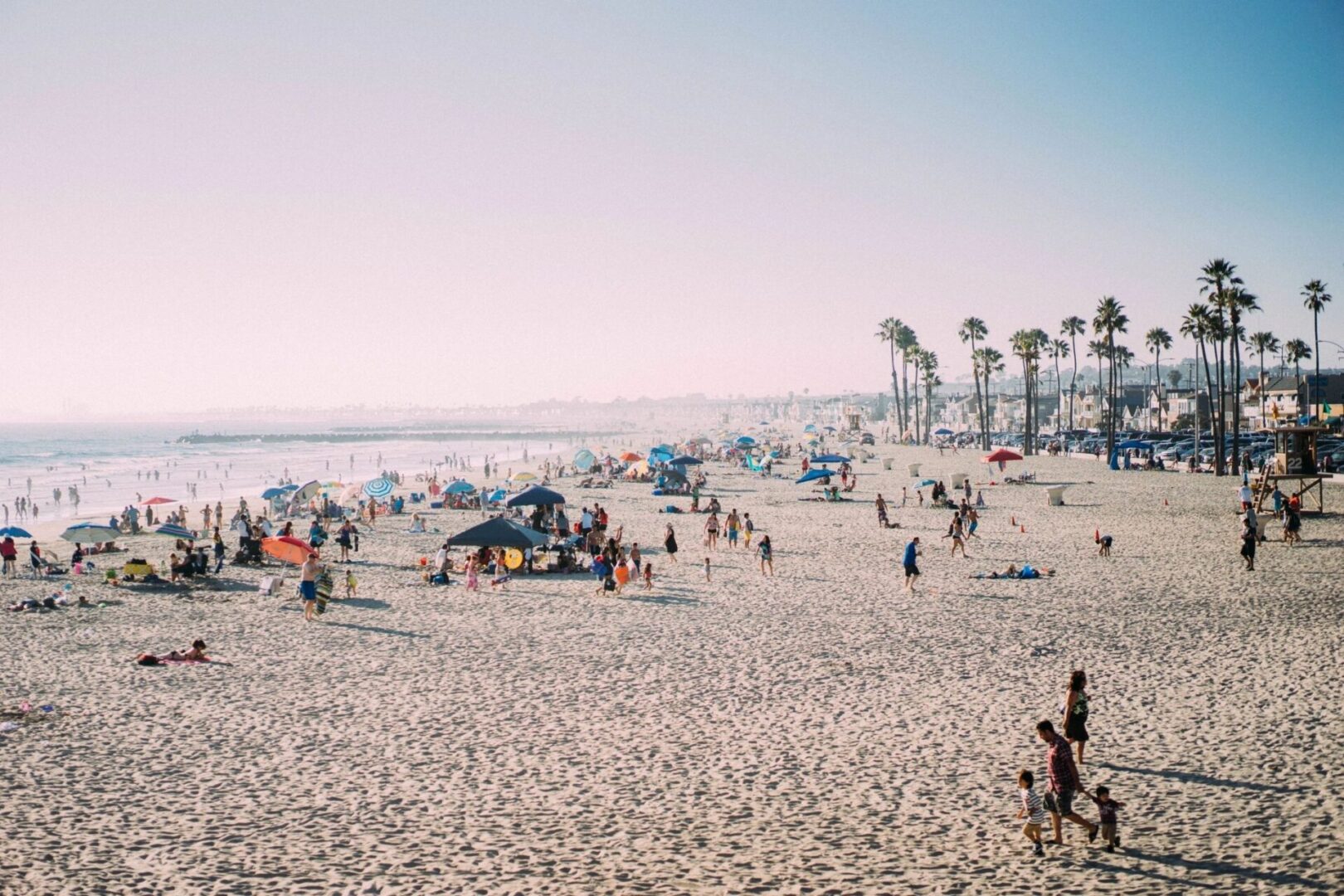 A beach with many people on it and some trees