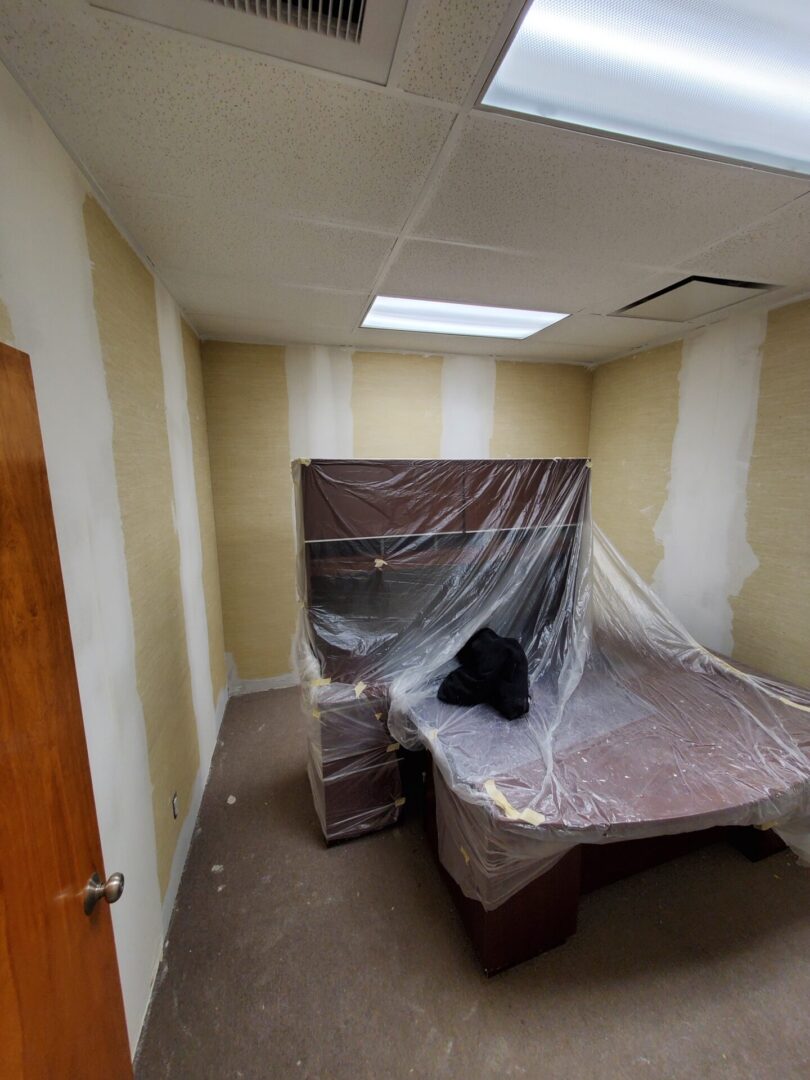 A room with a bed and a plastic tarp covering it.