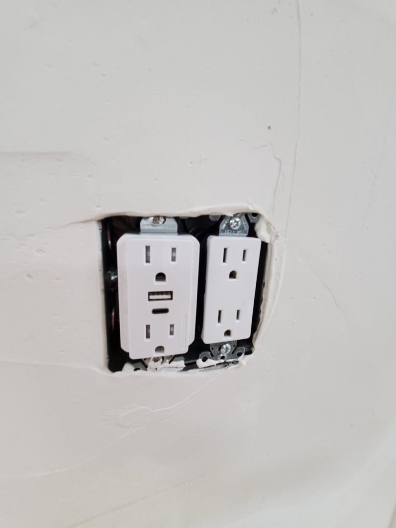 A white wall with two electrical outlets and one usb port.