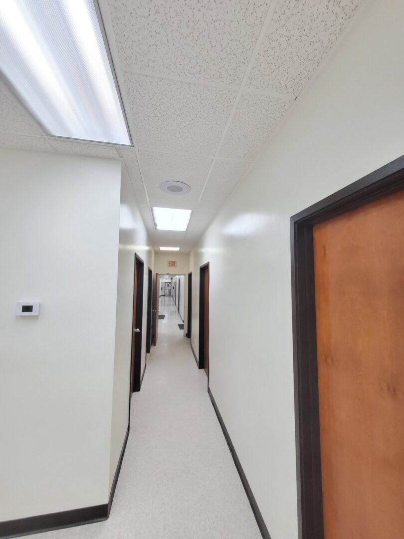 A hallway with many doors and white walls.