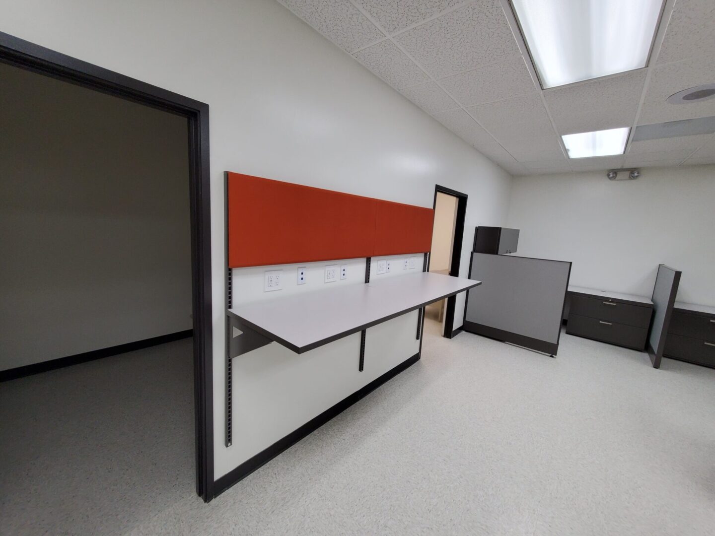 A room with two desks and a red wall.