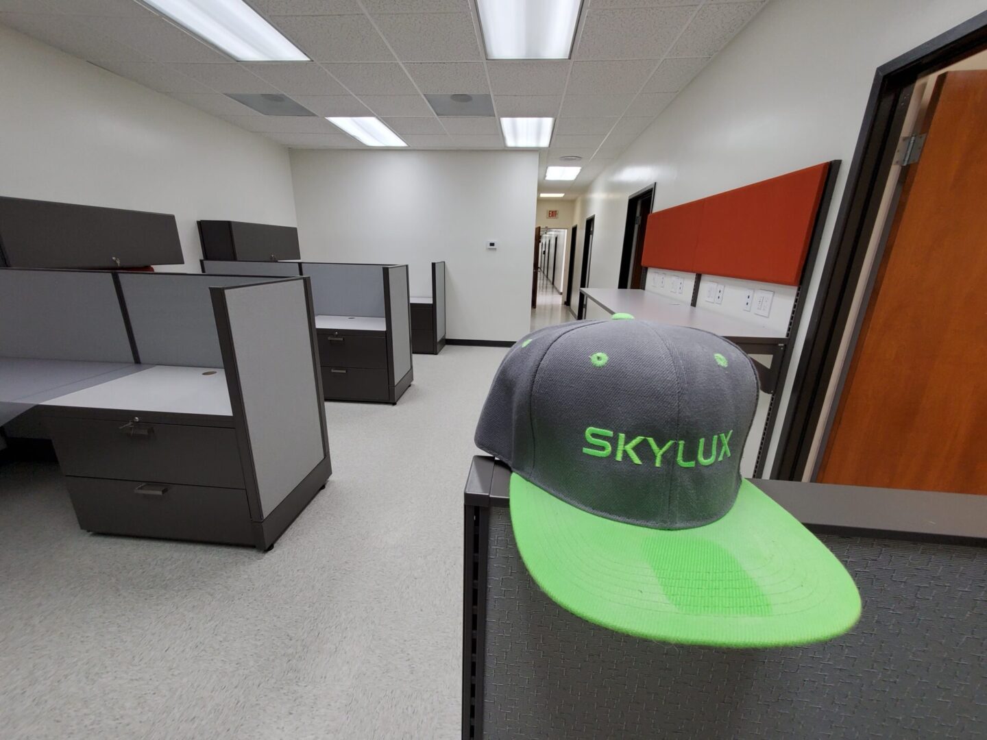 A hat is on top of the desk in an office.