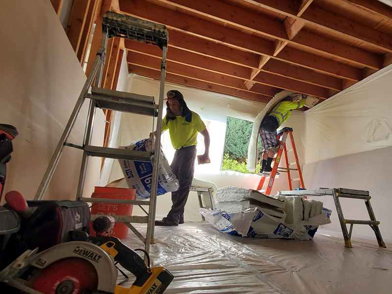 Two people working in a room under construction.