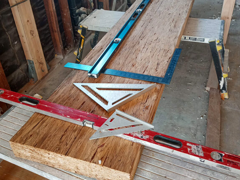 A wooden floor with some rulers and a triangle