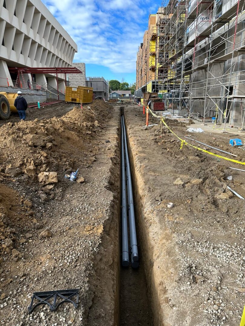 A pipe laying in the ground next to a building.