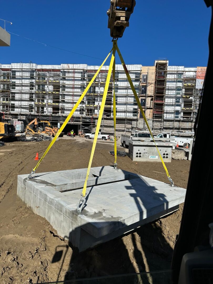 A crane is lifting concrete blocks in the sand.