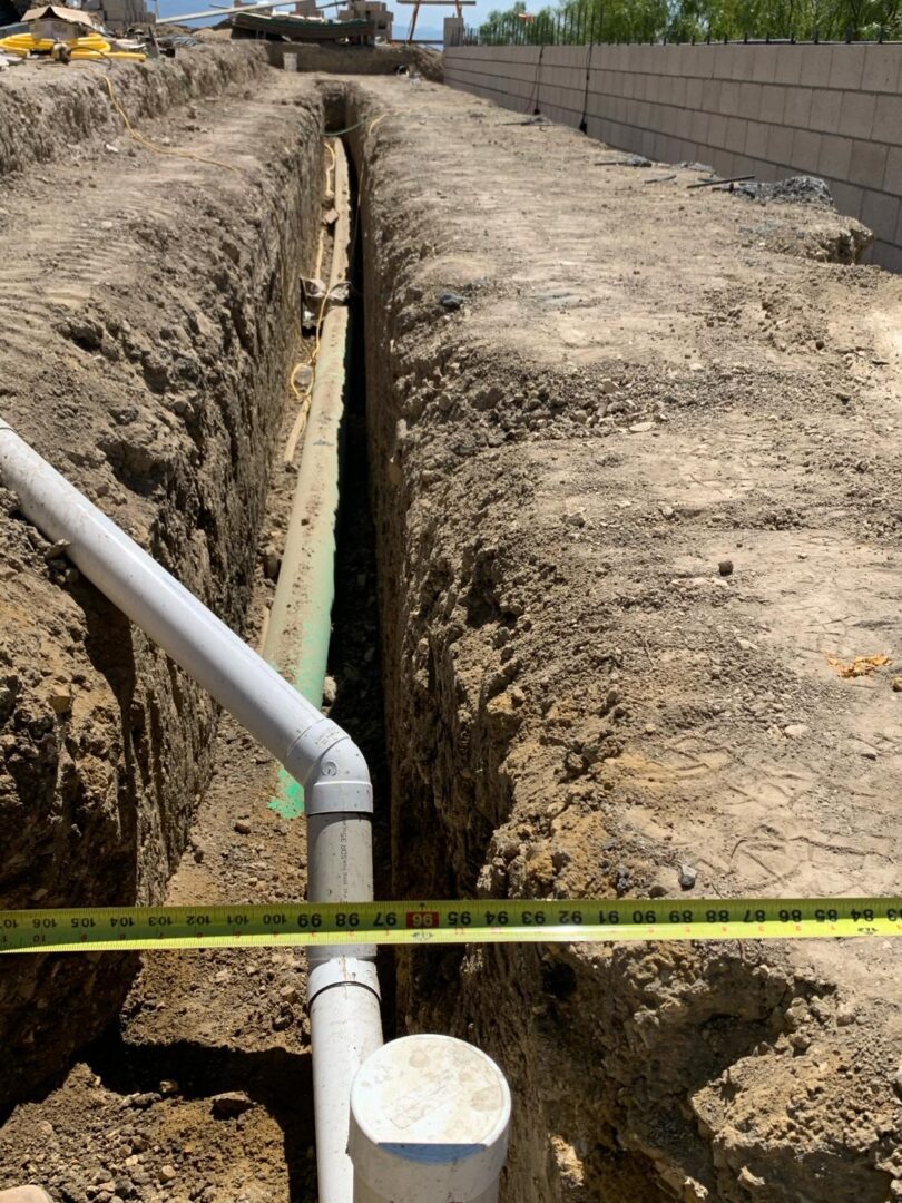 A pipe laying in the ground with a tape measure.