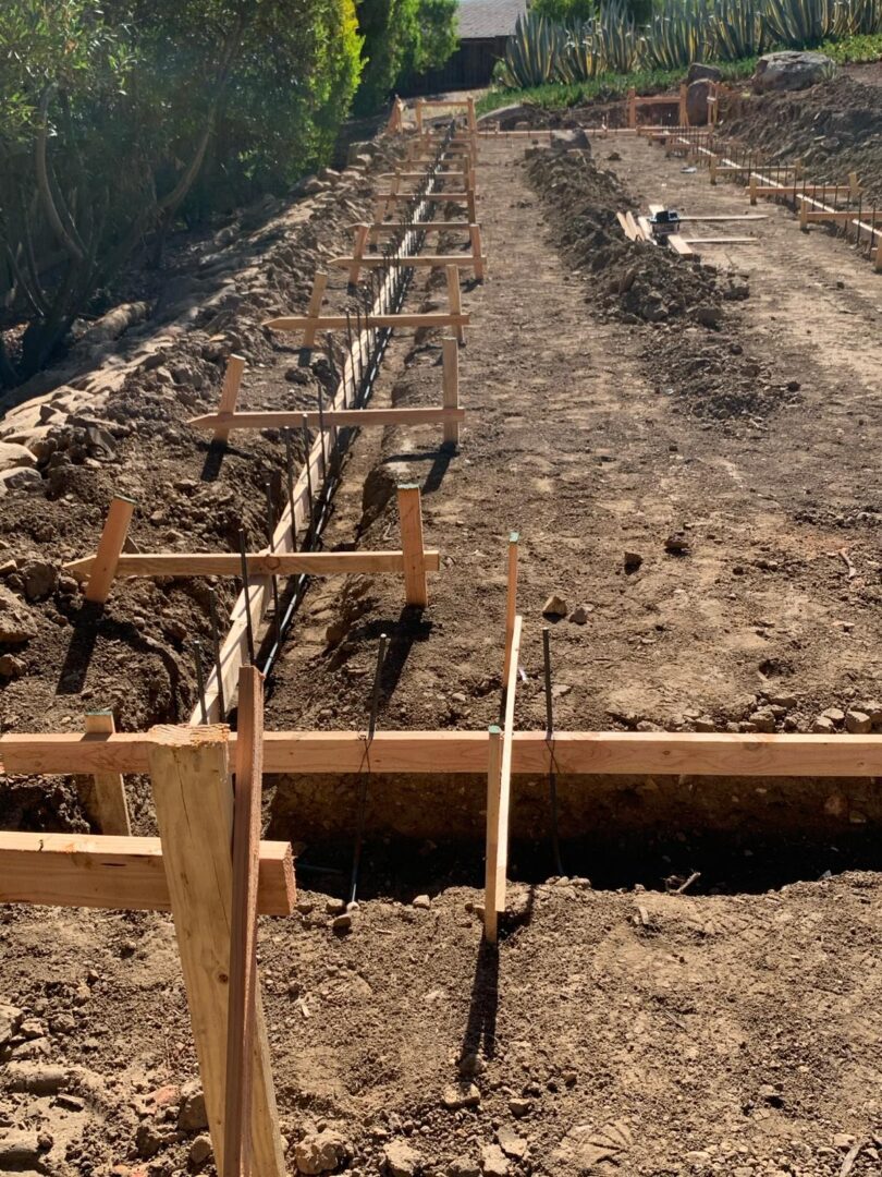 A dirt road with wooden posts and poles in the ground.