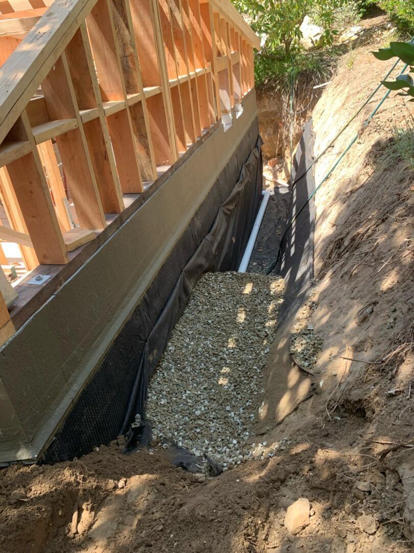 A view of the side of a house with gravel and dirt.