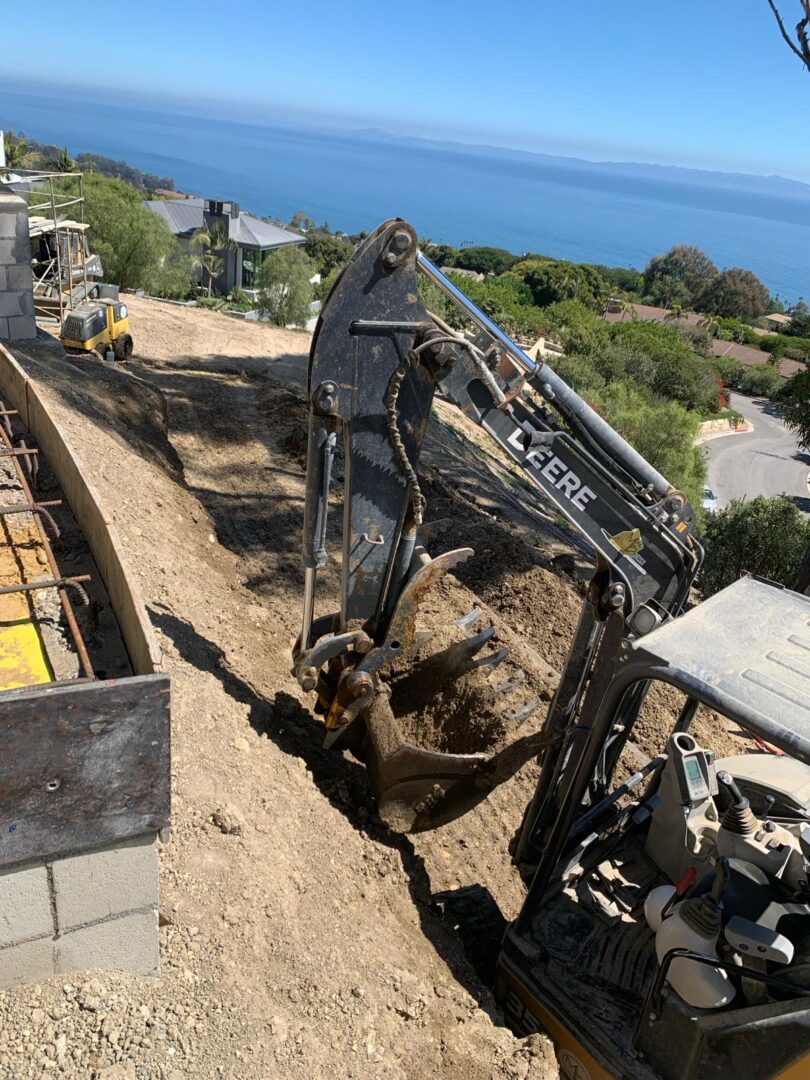 A black and silver excavator on top of a hill.